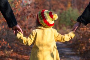 Florida Special Needs Estate Planning Lawyer, FL with a child in a yellow coat and hat walking holding their grown-ups' hands