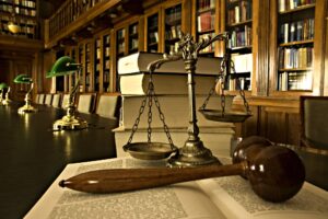 Litigation Lawyer Florida with a pile of books, a gavel, and scales on a long wooden table in a library