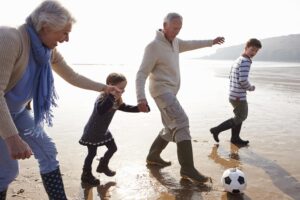 Living Trusts Lawyer Florida with grandparents playing soccer and holding hands on a beach with two grandkids